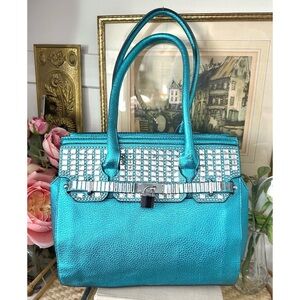 Turquoise handbag features a metallic textured finish, rhinestone embellishments